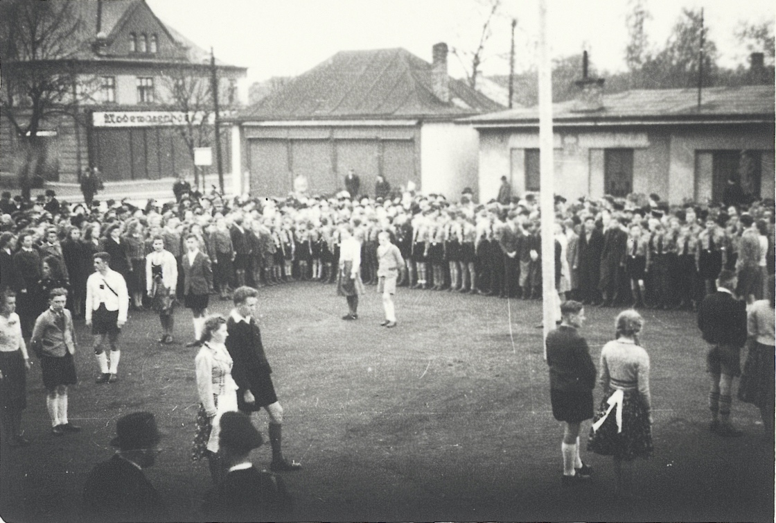 Záběry z oslav Májových ohňů v roce 1940 v Karvinné. Fotografováno na tržišti u Závodního hotelu: vlevo dům  čp. 1552 (textil Merta), malá budova uprostřed je čp. 1348, vpravo pak hasičská zbrojnice (čp. 1639).