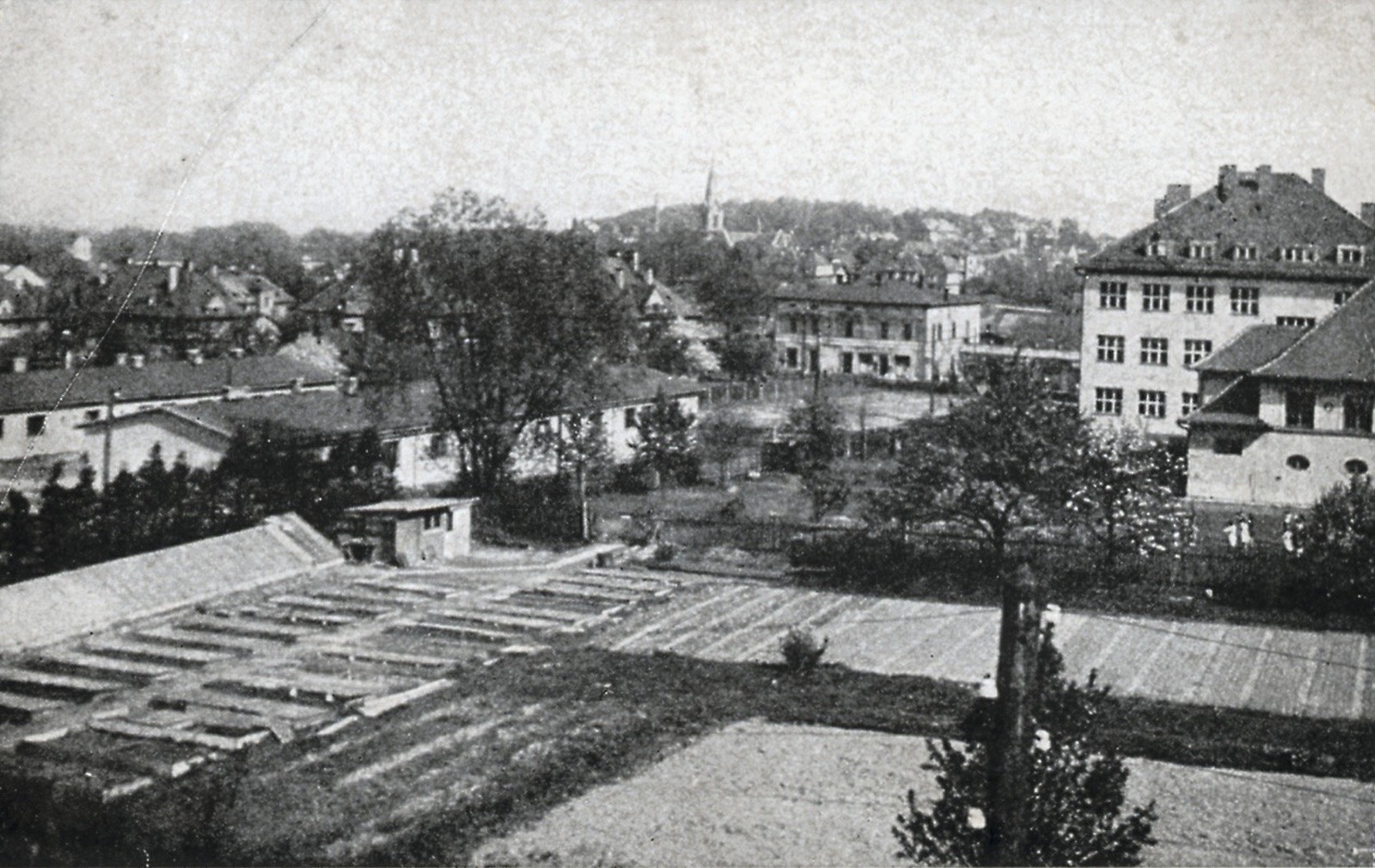 Vpravo část tělocvičny Masarykovy měšťanské školy, za ní budova Vyšší dívčí školy (tzv. Knedlíkárna). Vlevo zděné baráky čp. 135 (II) = původně kuchyně pro školy; a čp. 138 (II). Uprostřed snímku dům čp. 8 (Drogerie Matiasowitz).