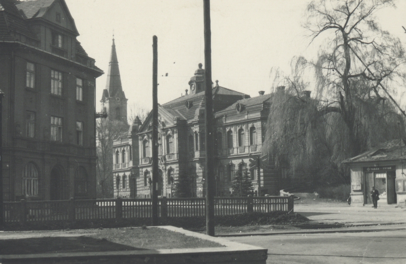 Vlevo průčelí městské spořitelny, v pozadí věž kostela sv. Jindřicha a městská radnice, vpravo trafika před železničním přejezdem.