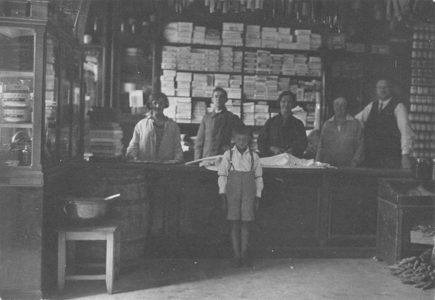 Interiér a personál obchodního domu Žižka (čp. 1610): zprava p. Rudolf Žižka, jeho žena Marie Žižková (roz. Molendová), sestra R. Žižky: Božena (Valová), obchodní příručí Beňa a druhá sestra Ludmila (Hudcová). Před prodejním pultem syn R. Žižky: Vladimír. (S laskavým svolením vnuka p. Žižky, z rodinného alba)
