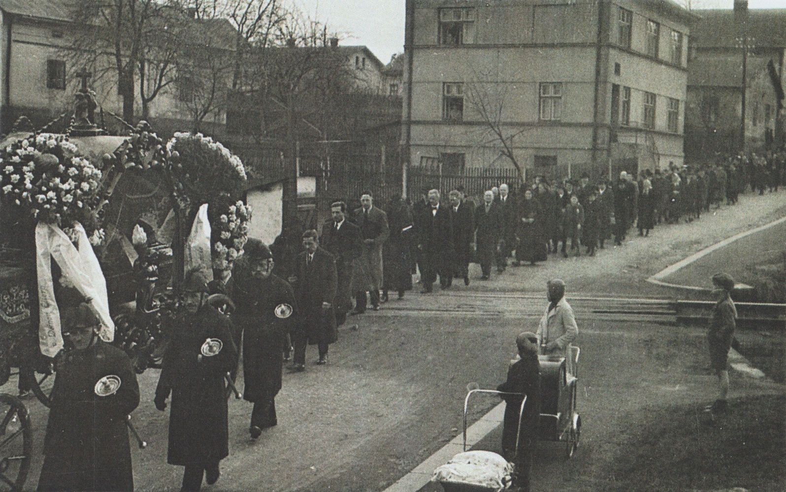 Pohřební průvod u přejezdu báňské vlečky na ulici Havlíčkova. Nalevo dům čp. 722, patrová budova uprostřed čp. 1706 (krejčí Bohuslav Obořil), vpravo část domu čp. 241. (S laskavým svolením p. Jana Polakoviče, ze soukromé sbírky)