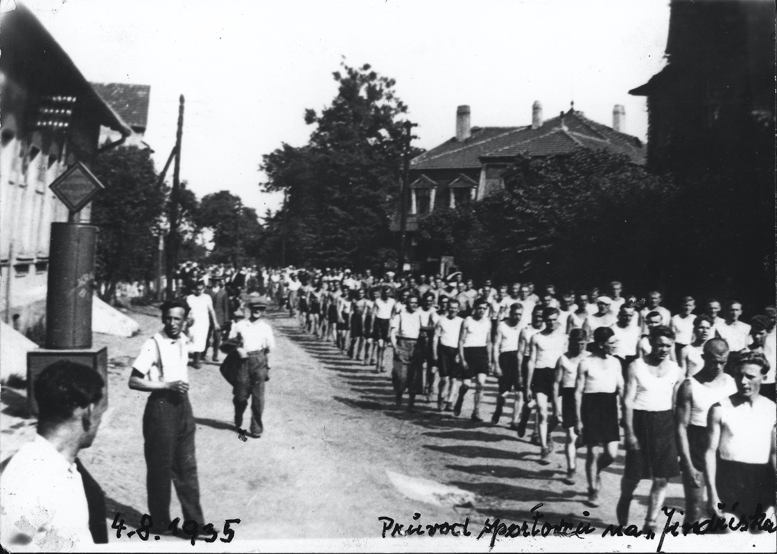 Průvod sportovců 12.okresu FPT a 55.powiatu FPK ke společnému cvičení 4.8.1935 v Karvinné (Komenského ulice, v pozadí budova Polské družstevní spořitelny)