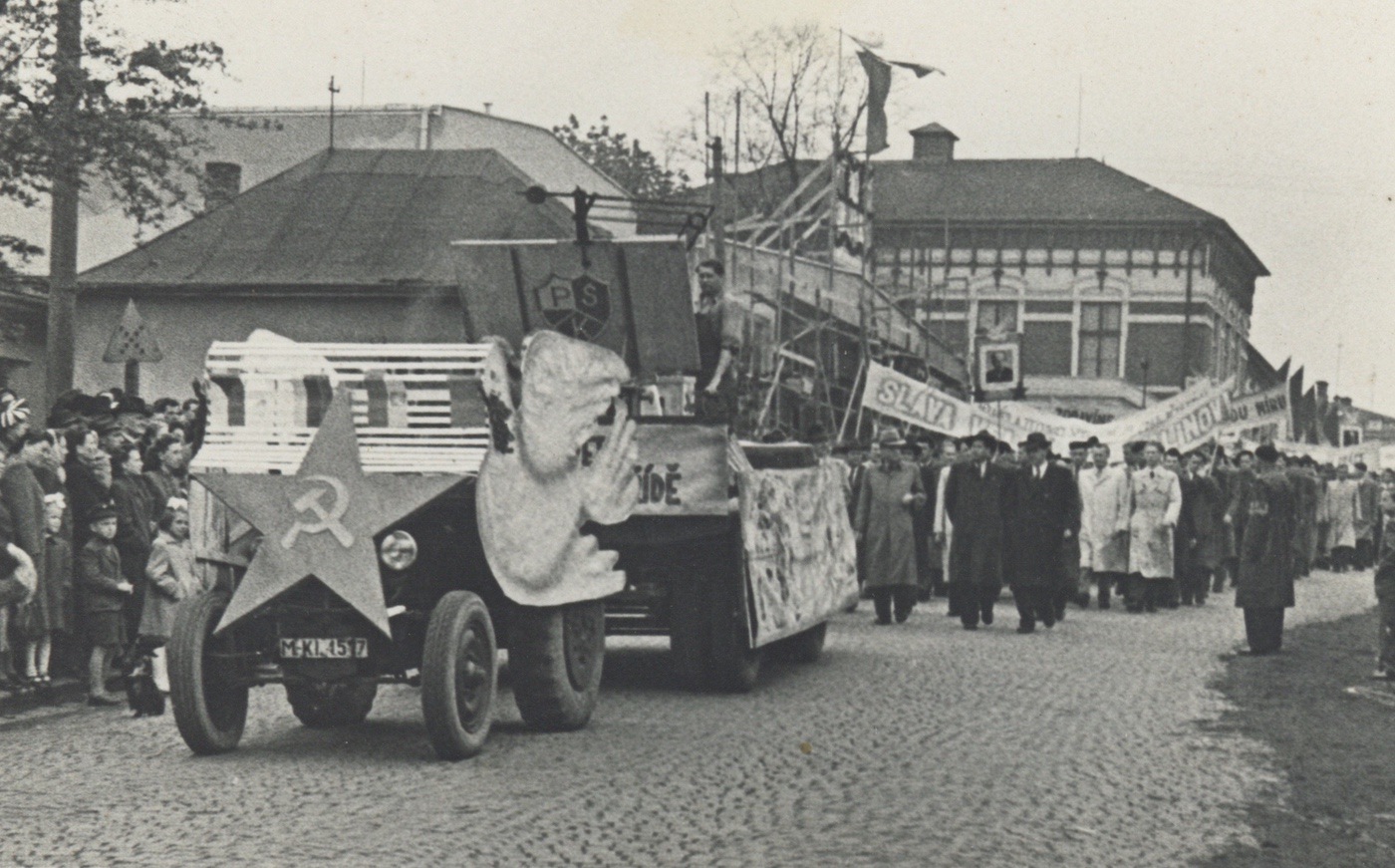 Prvomájový průvod procházející Komenského ulicí v roce 1951. V pozadí budova Závodního hotelu.