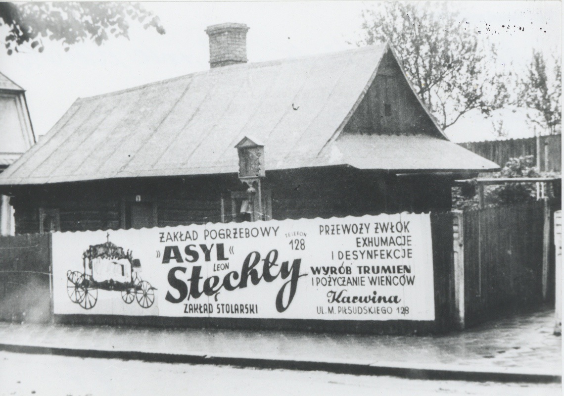 Dům čp. 6 (Lidový léčitel Szwachuła). Před domem Boží muka. Na plotě reklamní plakát na Pohřební ústav Asyl a stolařství Leon Stechły.