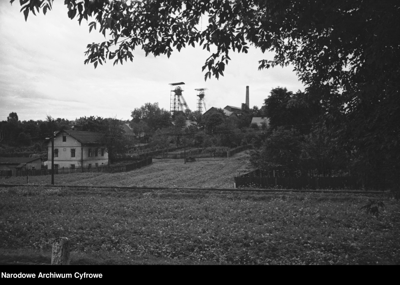 Vlevo dům čp. 712, vpravo za ním těžní věže dolu Gabriela. (Autor: Henryk Poddębski, odkaz na originál: Narodowe Archiwum Cyfrowe = klik na obrázek)