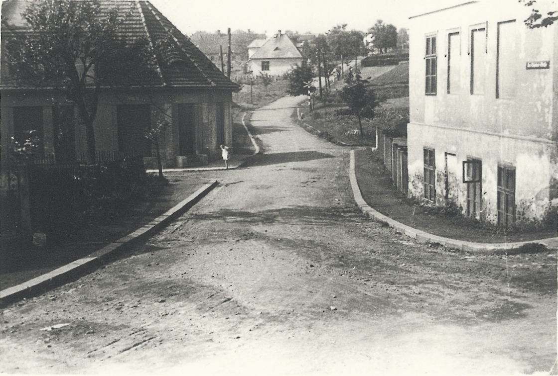 Vlevo dům čp. 299 (Kůže - obuvnické potřeby Borák), uprostřed za přejezdem dům čp. 1608 (Krejčovství Kloda), vpravo v popředí pak dům čp. 86