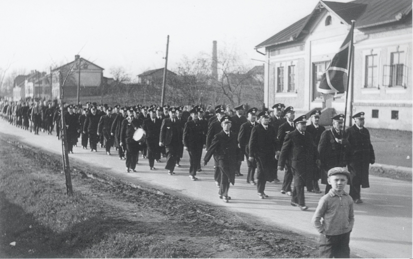 Zprava doleva: budova čp. 978 (Prodejna potravin Postęp), dům čp. 689, dům čp. 935 (Řeznictví Halfar) a čp. 132 (Lékárna Langer). Záběr z blíže neurčených májových slavností za německé okupace v roce 1941.