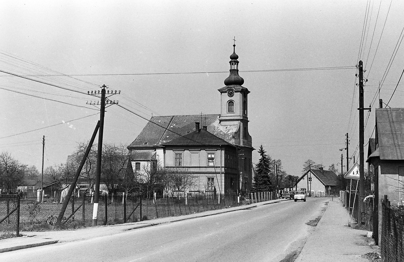 Vlevo budova Farního úřadu v Loukách čp. 29, za ní kostel sv. Barbory (se svolením autora fotografie p. Bronislava Filipczyka, ze soukromé sbírky)