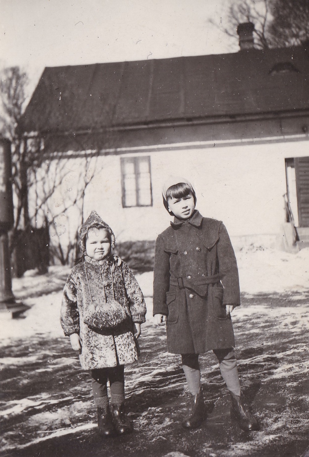 Helena Lukoszová s bratrem Janem před domem čp. 13, který stál v blízkosti garáží (Zdroj: E. Schweserová, P. Bindač: SOLCA Tajemství zámeckého parku = KLIK NA FOTOGRAFII. Foto z rodinné sbírky Heleny Lukoszové)