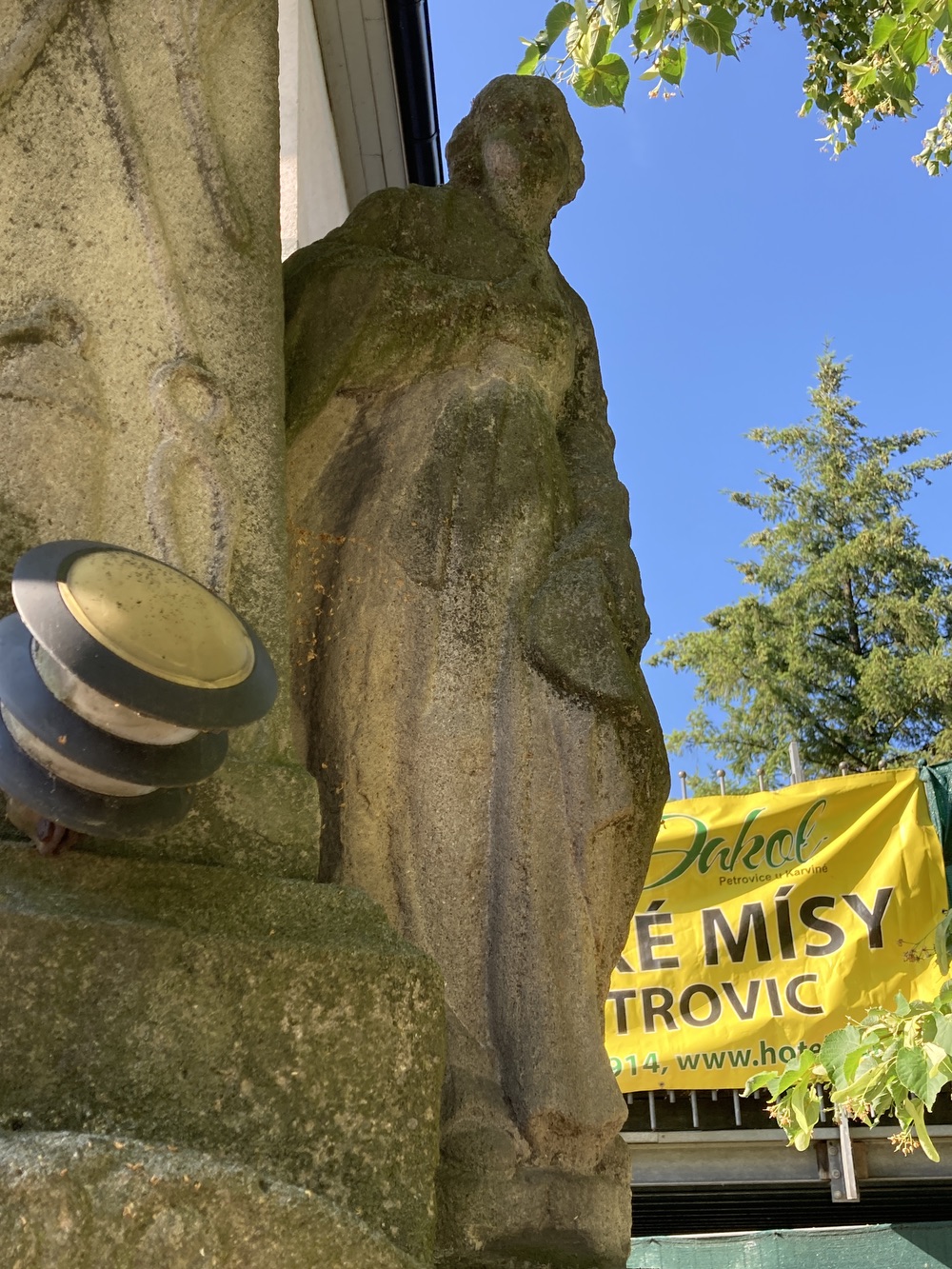 Sousoší Malé Kalvárie s reliéfem sv. Veroniky a postavami Panny Marie (vlevo) a sv. Jana (vpravo) po stranách kříže, z roku 1858 (Petrovice u Karviné, u čp. 153). KULTURNÍ PAMÁTKA