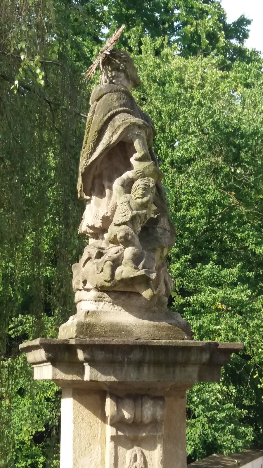 Barokní socha svatého Jana Nepomuckého z roku 1747 za presbytářem kostela Povýšení sv. Kříže ve Fryštátě. Původně stála socha na náměstí, přibližně v místech před dnešním pomníkem T. G. Masaryka.