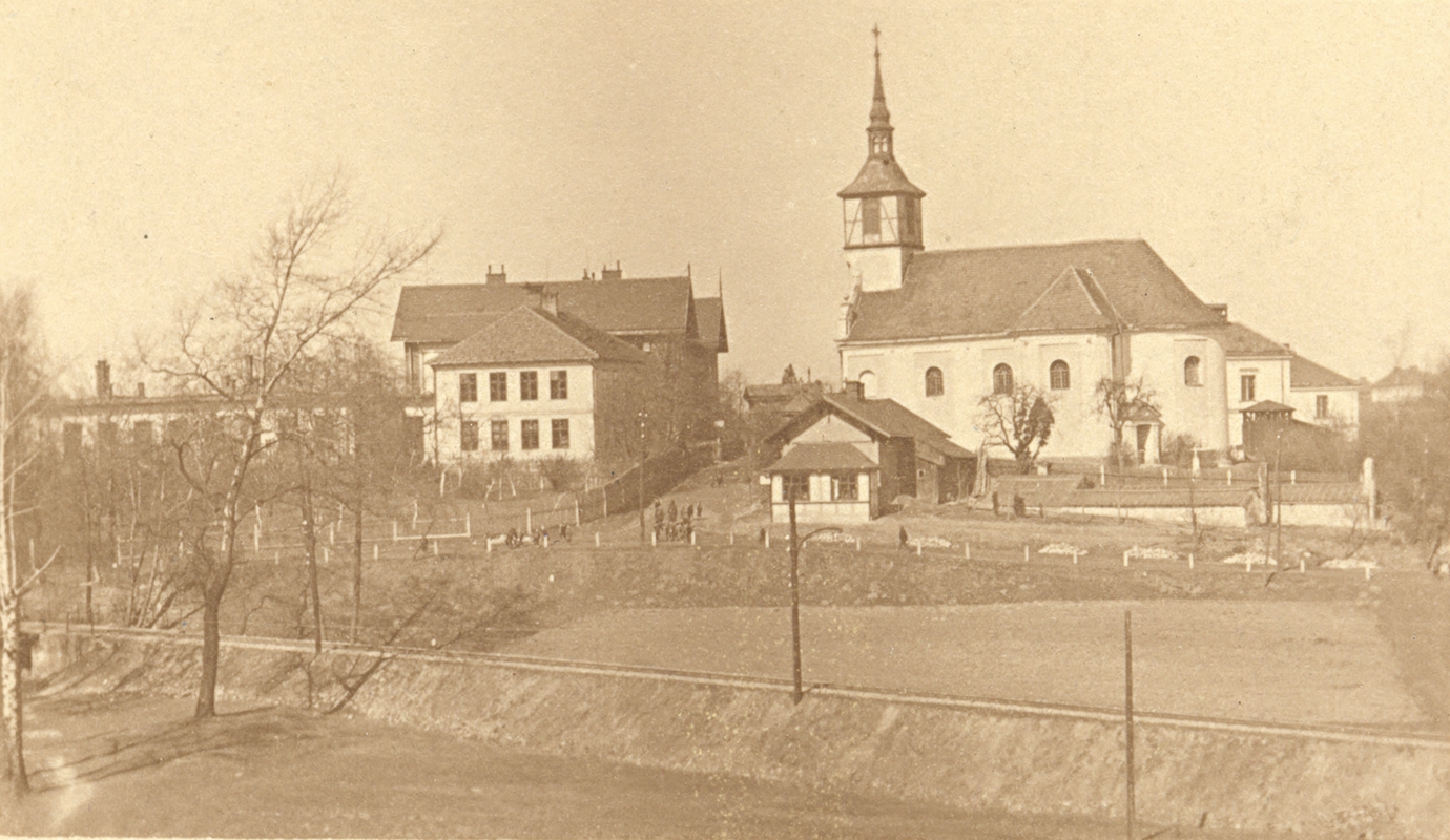 Pohled na budovy dvou škol – Bílé a Červené, spolu s kostelem sv. Petra z Alkantary. V popředí domek čp. 49.