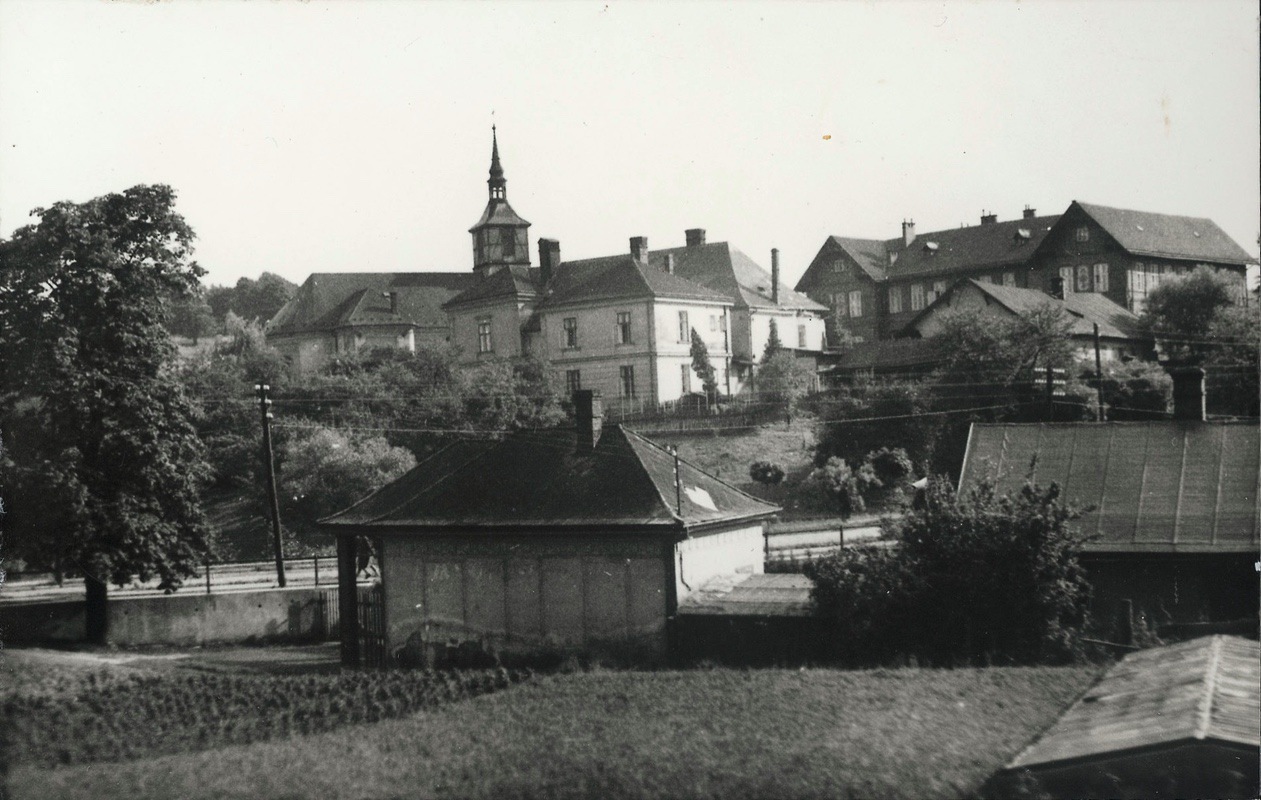 V popředí zahradnictví Dvořák, za silnicí budovy farního úřadu (čp. 12), tzv. Červená škola a kostel sv. Petra z Alkantary
